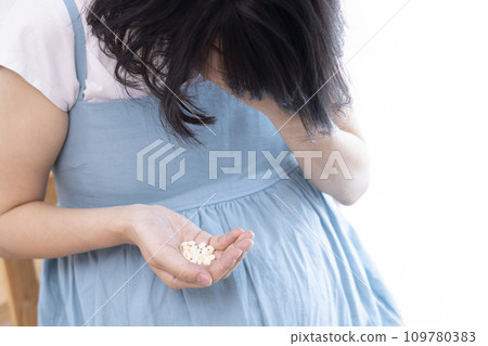 Image of a woman holding her head and holding medicine 109780383