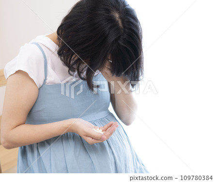 Image of a woman holding her head and holding medicine Image of a woman holding her head and holding medicine 109780384
