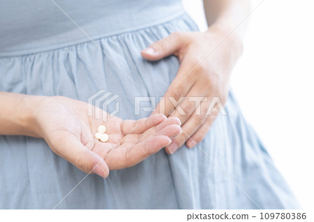 Image of a pregnant woman taking medicine 109780386