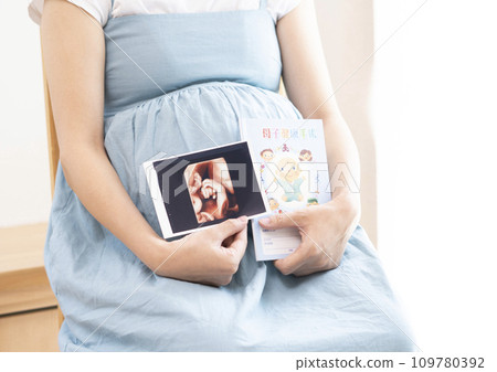 An image of a pregnant woman holding an ultrasound photo and a maternity record book An image of a pregnant woman holding an ultrasound photo and a maternity record book 109780392