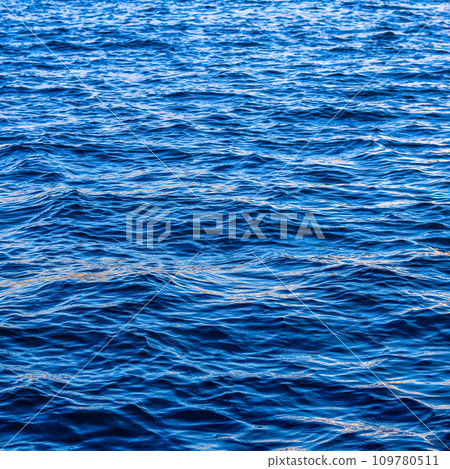 Blue sea waves in sunshine glow as surface background. Summer holidays and coastal nature concept Blue sea waves in sunshine glow as surface background. Summer holidays and coastal nature concept 109780511