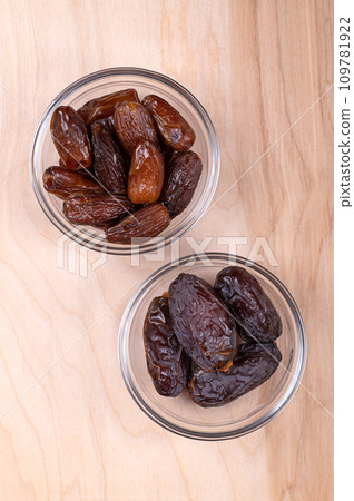 Deglet Nour and Medjool dates, in glass bowls, on a wooden panel, from above. Sun-dried and sweet cultivars of the most common Deglet Noor and the much larger and soft Medjoul or also Majhool dates. Deglet Nour and Medjool dates, in glass bowls, on a wooden panel, from above. Sun-dried and sweet cultivars of the most common Deglet Noor and the much larger and soft Medjoul or also Majhool dates. 109781922