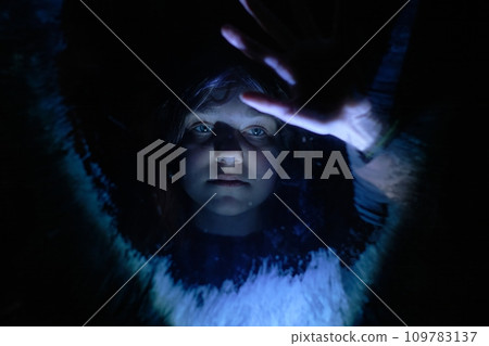 A lonely girl behind glass in a dark room is waiting for help 109783137