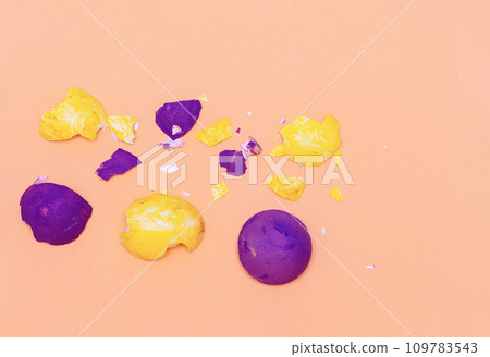 Bright yellow and purple eggshells on pastel paper background. Bright yellow and purple eggshells on pastel paper background. 109783543