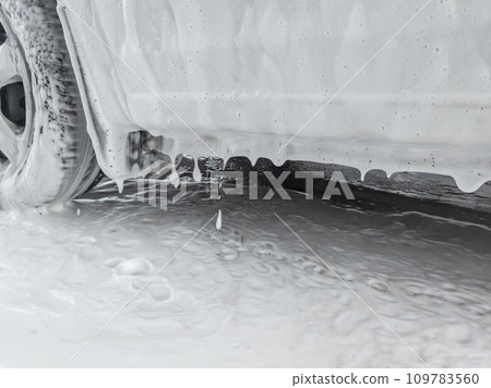 soap sud dripping from side of white car during car wash 109783560