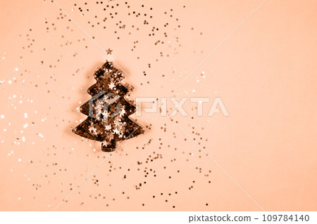 Shape in the form of a Christmas tree on a peach background. color of 2024. Shape in the form of a Christmas tree on a peach background. color of 2024. 109784140