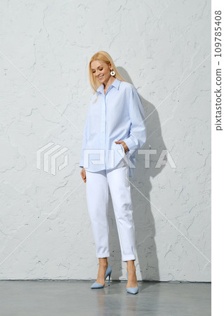 Cute woman in blue striped shirt, white jeans and stilettos looking down Cute woman in blue striped shirt, white jeans and stilettos looking down 109785408