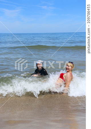 Family enjoying rest bathing in sea. Mother with daughter playing with sea waves 109786455