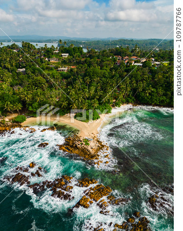 Tropical beach aerial view, drone shot of coastline with lush palm trees, waves crashing on rocks, secluded sandy shore for travel and nature themes Tropical beach aerial view, drone shot of coastline with lush palm trees, waves crashing on rocks, secluded sandy shore for travel and nature themes 109787766
