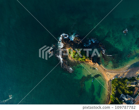 Aerial view of tranquil coastal vista with lush greenery and azure waters, ideal for travel brochures and postcards promoting serene vacations and tropical getaways. Parrot rock island in Sri Lanka. Aerial view of tranquil coastal vista with lush greenery and azure waters, ideal for travel brochures and postcards promoting serene vacations and tropical getaways. Parrot rock island in Sri Lanka. 109787782