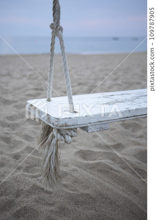 Wooden swing on the beach. The coast of the Indian Ocean. A deserted beach. The concept of summer holidays. Copy space. Vertical photo. Wooden swing on the beach. The coast of the Indian Ocean. A deserted beach. The concept of summer holidays. Copy space. Vertical photo. 109787905