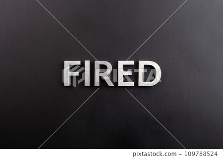 the word fired laid with silver metal letters on flat black surface 109788524