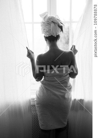 Portrait on back view of bare shoulder woman looking at the window in black and white Portrait on back view of bare shoulder woman looking at the window in black and white 109788878