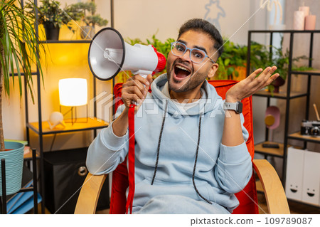 Indian man talking with megaphone, proclaiming news, loudly announcing advertisement promotion sale 109789087