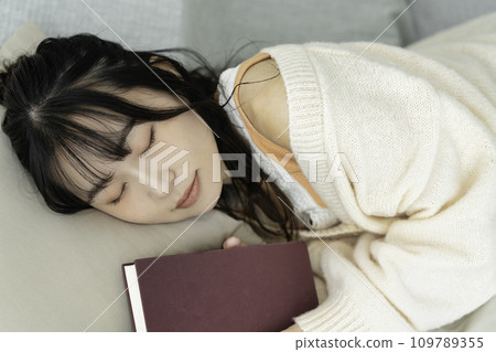 Young woman lying down holding a book Young woman lying down holding a book 109789355