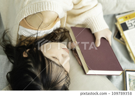 Young woman lying down holding a book 109789358