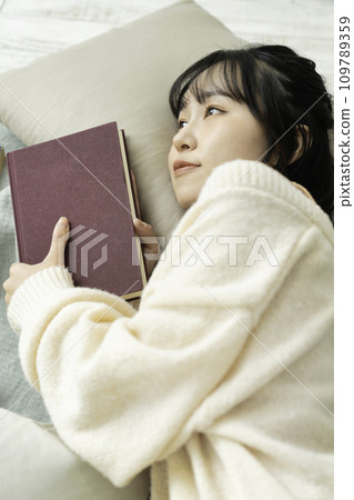 Young woman lying down holding a book 109789359