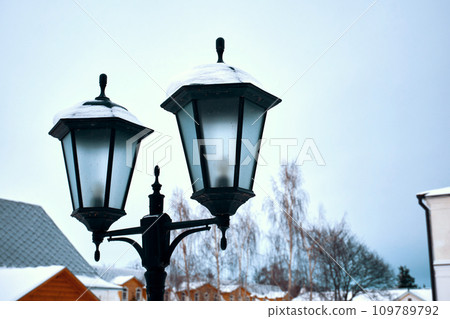 Street lamp close-up during the day against the backdrop of a winter village Street lamp close-up during the day against the backdrop of a winter village 109789792