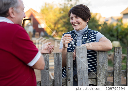Positive mature man and woman standing near fence in garden 109790694