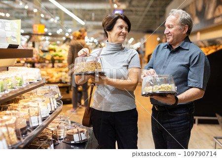 Husband and wife choose cake in store for festive dinner Husband and wife choose cake in store for festive dinner 109790714