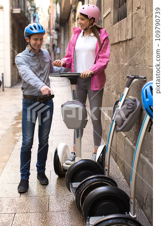 Young couple guy and girl walking on segway in streets of european city 109790739