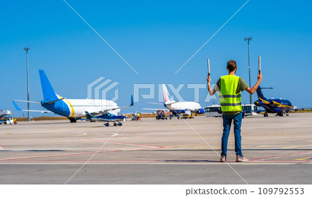 Dispatcher geaturing signs directing the plane Dispatcher geaturing signs directing the plane 109792553
