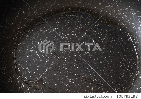 oil dripping into a frying pan 109793198