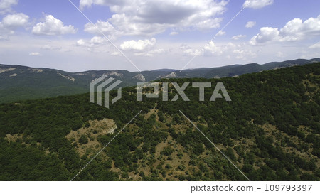 Amazing endless landscape of the high mountain ranges covered by green trees and shrubs against the blue cloudy sky in summer day. Shot. Beautiful mountain scenery Amazing endless landscape of the high mountain ranges covered by green trees and shrubs against the blue cloudy sky in summer day. Shot. Beautiful mountain scenery 109793397
