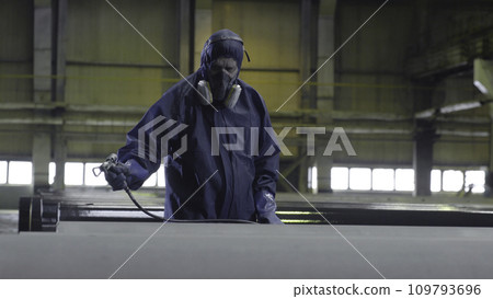 Male holding spray gun and painted steel. Man paints pipe atomizer 109793696