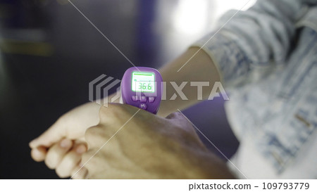 Checking fever of a visitor with a digital thermometer in the wrist area. Meida. Concept of protect from Coronavirus, COVID 19 outbreak and healthcare. Checking fever of a visitor with a digital thermometer in the wrist area. Meida. Concept of protect from Coronavirus, COVID 19 outbreak and healthcare. 109793779