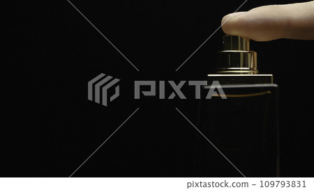 Fragrance luxury bottle contents in dark spraying slow motion. Perfume bottle spray on black background. Spraying Cologne on a black background. lose up of handsome young business man using perfume or 109793831