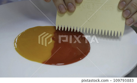 Smearing jam on a plate. Two kinds of jam smeared on the plate with a spatula 109793883