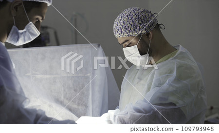 Details of a real surgery in the sterile operating theatre. Action. Medical background of doctors wearing sterile uniform and face mask at work at the hospital. Details of a real surgery in the sterile operating theatre. Action. Medical background of doctors wearing sterile uniform and face mask at work at the hospital. 109793948