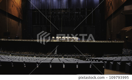 Meeting room before the educational conference. Media. Man going up the stairs among empty rows of chairs in front of the stage with beige armchairs. Meeting room before the educational conference. Media. Man going up the stairs among empty rows of chairs in front of the stage with beige armchairs. 109793995