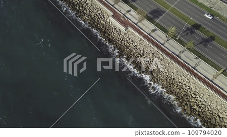 Aerial flying shot following cars on the highway alongside a rocky coast. Stock. Aerial view of Coastline along and highway 109794020