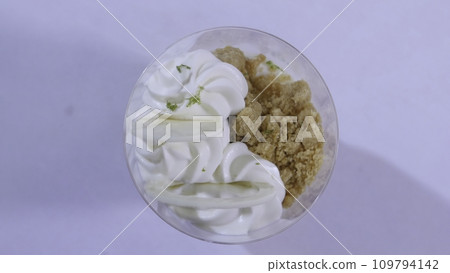 Sweet dessert in glass with biscuit, whipped cream. Ice cream with whipped cream close up Sweet dessert in glass with biscuit, whipped cream. Ice cream with whipped cream close up 109794142
