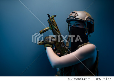 sexy girl soldier in a helmet, armed with an automatic rifle, in military clothes on a blue background 109794156