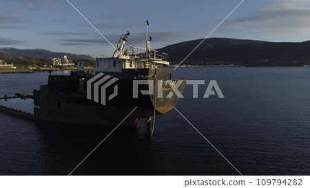 Close-up of old and rusty sunken ship on a shoal against the coastline. Shot. Old seagoing vessel 109794282