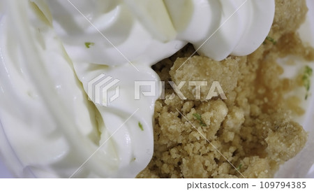 Sweet dessert in glass with biscuit, whipped cream. Ice cream with whipped cream macro Sweet dessert in glass with biscuit, whipped cream. Ice cream with whipped cream macro 109794385