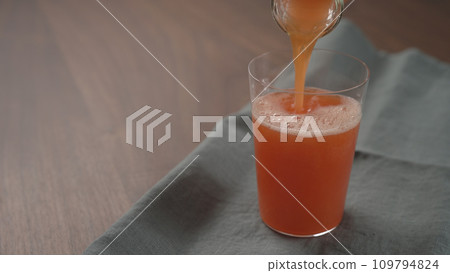 pour red orange drink into tumbler glass with copy space pour red orange drink into tumbler glass with copy space 109794824