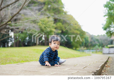 一個 1 歲的幼兒穿著第一雙鞋在充滿大自然的公園裡快樂地玩耍 109795167