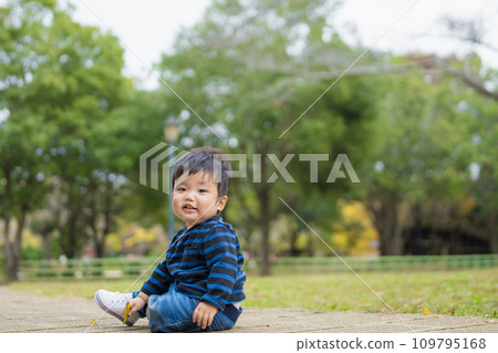 一名 1 歲的幼兒穿著第一雙鞋，在充滿大自然的公園裡開心玩耍。 109795168
