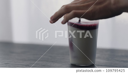 mix natural berry juice in organic yogurt in tumbler glass on black wood table with copy space 109795425