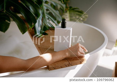 Bottle of hygiene product for bathing on bathtub and female hand 109796062