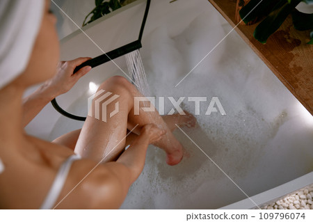 Cropped shot of woman washing her long slim legs with shower in bath 109796074
