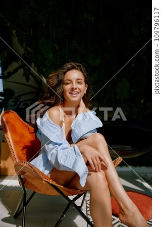 Young sensual woman relaxing in chair of home backyard enjoying sunny day Young sensual woman relaxing in chair of home backyard enjoying sunny day 109796117