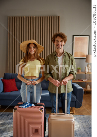 Happy family couple going for trip posing with packed luggage suitcases at home Happy family couple going for trip posing with packed luggage suitcases at home 109796133