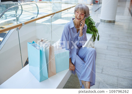 Smiling senior woman relaxing after shopping speaking by phone Smiling senior woman relaxing after shopping speaking by phone 109796262