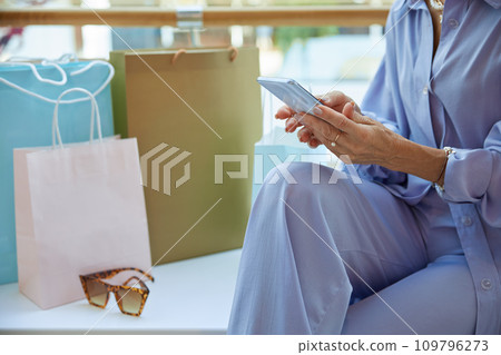 Elegant mature woman after shopping chatting social media in smartphone Elegant mature woman after shopping chatting social media in smartphone 109796273