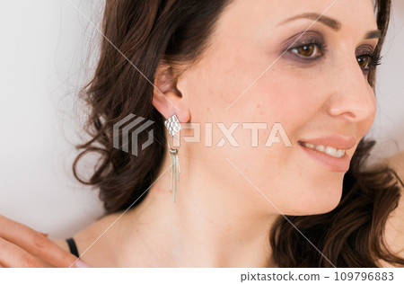 Jewelry and close-up earrings in a beautiful female ear - women's accessories, silver trendy earrings. Handmade jewellery concept Jewelry and close-up earrings in a beautiful female ear - women's accessories, silver trendy earrings. Handmade jewellery concept 109796883